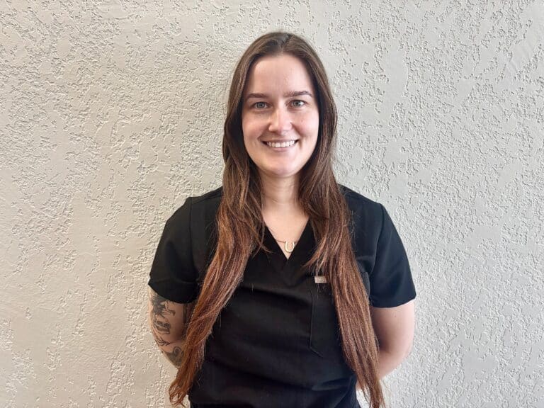 Zoe Vass, Registered Massage Therapist at Edge Health Barrie, smiling in black scrubs