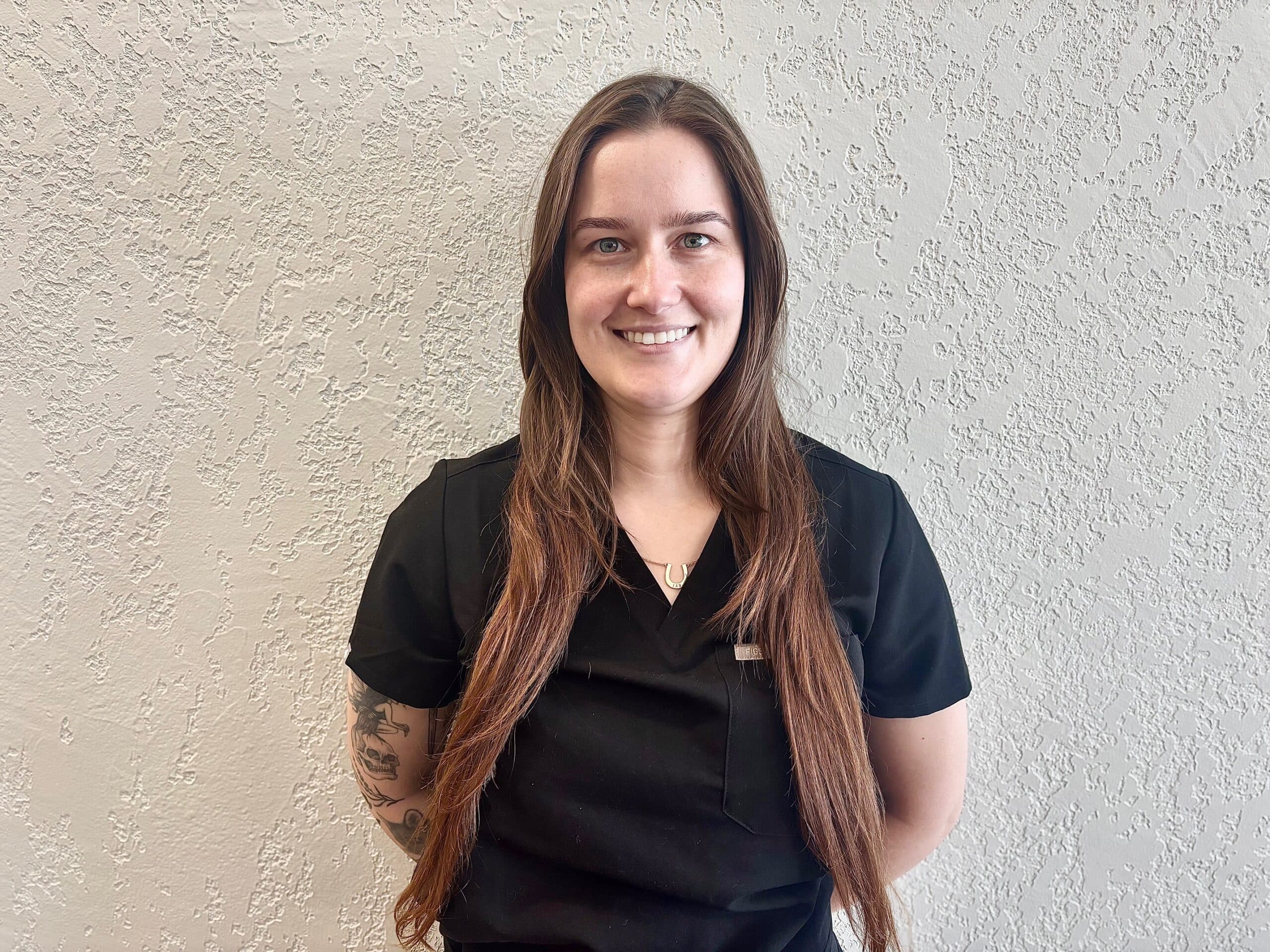 Zoe Vass, Registered Massage Therapist at Edge Health Barrie, smiling in black scrubs